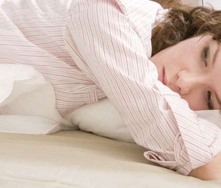 Frau liegt sorgenvoll im Bett Wochenbettdepression: Definition, Symptome, Behandlung