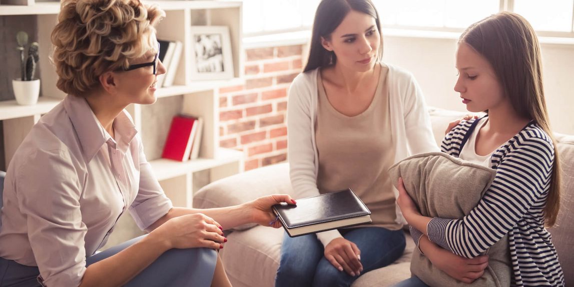 Psychologin spricht mit Kind und Mutter