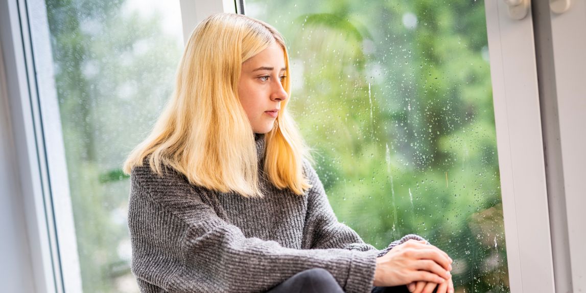 Mädchen schaut traurig aus dem Fenster