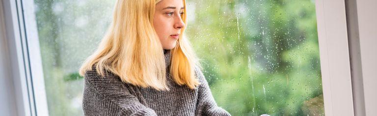 Mädchen schaut traurig aus dem Fenster