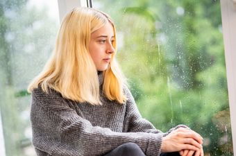 Mädchen schaut traurig aus dem Fenster