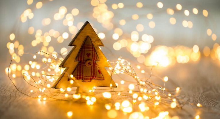 Weihnachtsbaum aus Holz mit Lichterkette auf einem Holztisch
