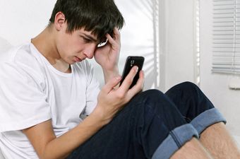 Junger Mann schaut depremiert in sein Handy