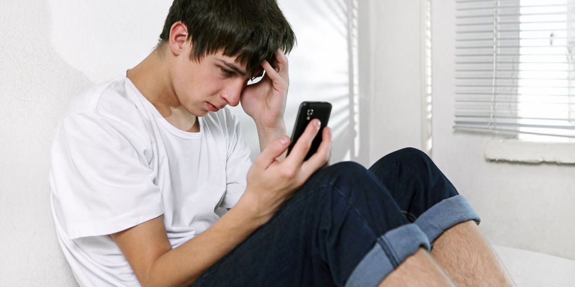 Junger Mann schaut depremiert in sein Handy