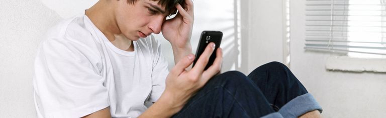 Junger Mann schaut depremiert in sein Handy