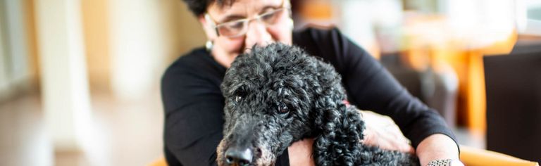 Frau drückt Hund an sich